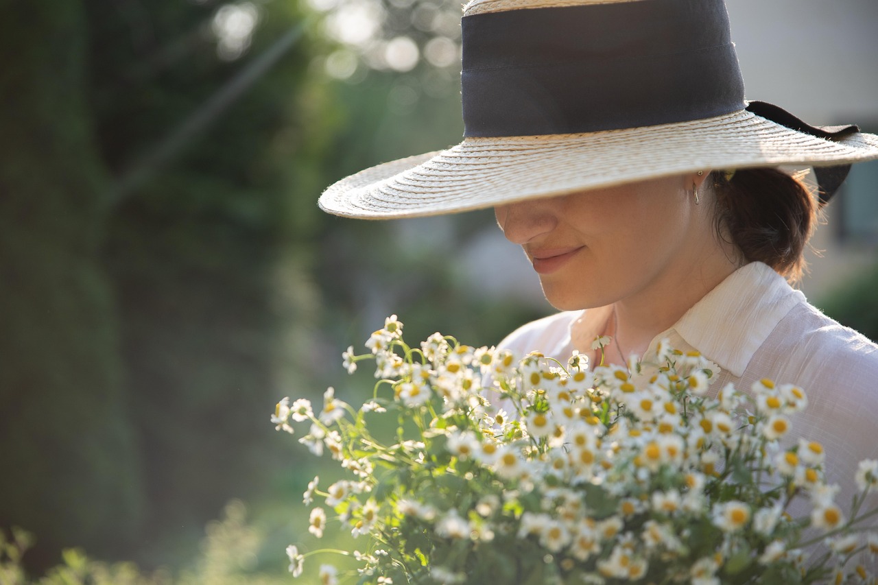 Smiling young woman in a hat among daisies, enjoying the sun, mindful of mineral sunscreen for pregnancy.