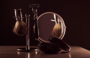 A vintage shaving brush, razor, and cream next to a mirror, illustrating skincare tips for expecting parents.