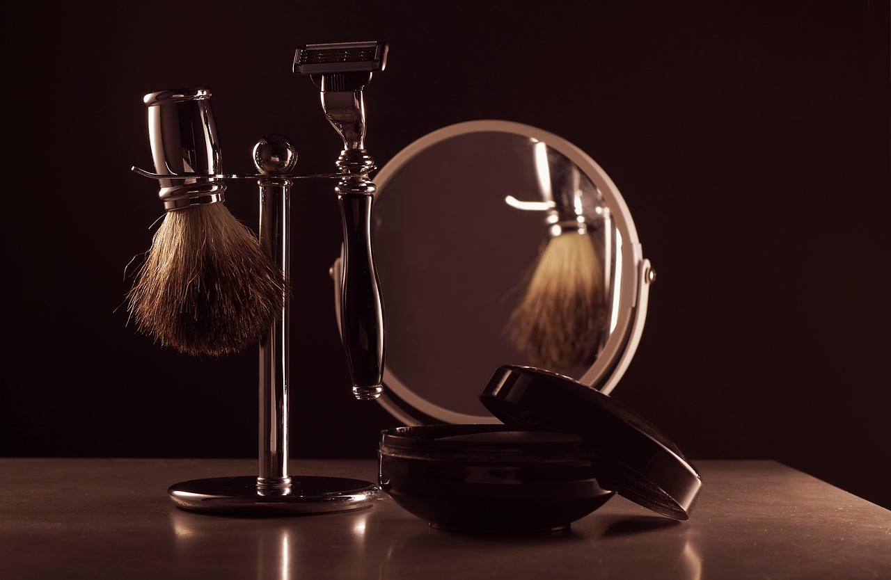 A vintage shaving brush, razor, and cream next to a mirror, illustrating skincare tips for expecting parents.