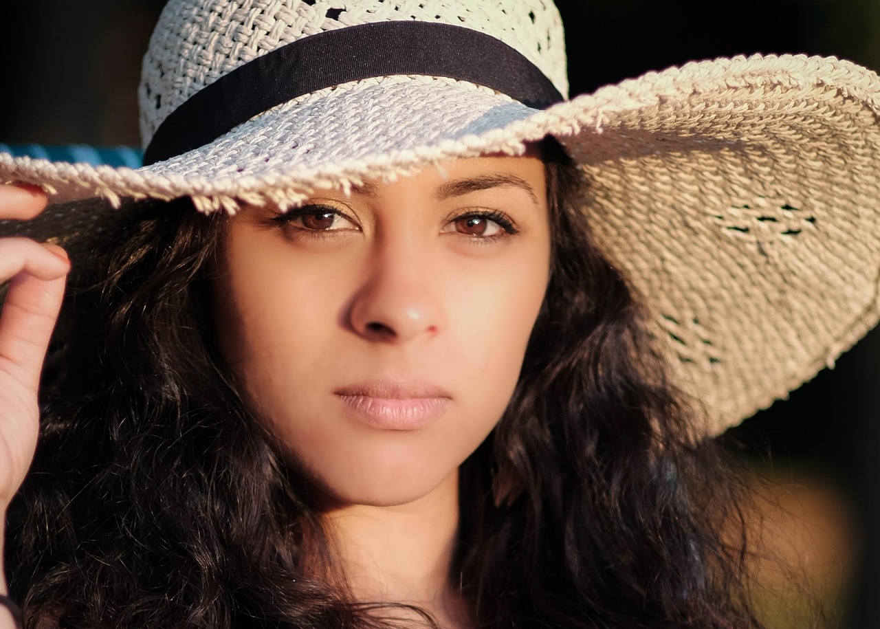 Brunette woman in a wide sun hat, emphasizing safe sun protection for mineral sunscreen and pregnancy.