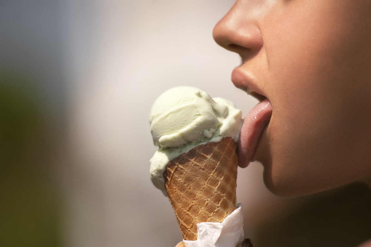 A woman happily licks a scoop of ice cream, a sweet moment before diving into your gentle guide to mineral sunscreen for preg