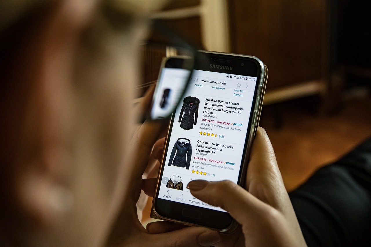 Hands hold a smartphone displaying an online store with baby clothes, helping expecting parents find Black Friday deals.