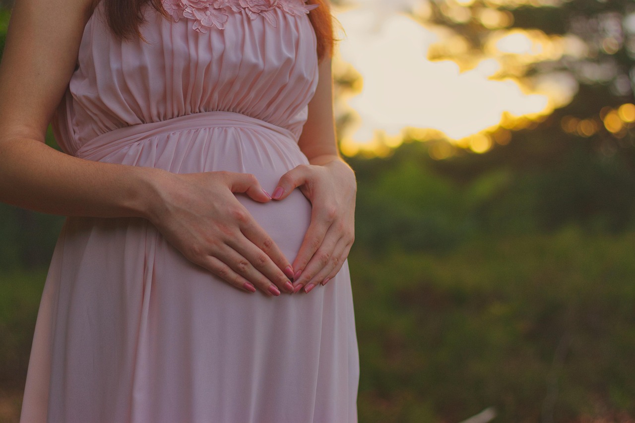 A pregnant woman cradles her baby, concerned about product identification using the SafeMom app.