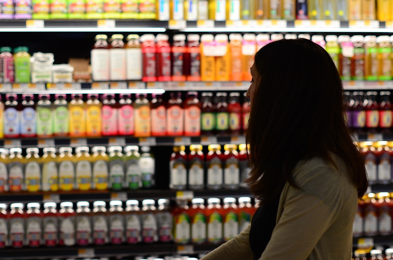 Woman in a grocery store examines a drink bottle, reflecting SafeMom product identification scan limits.