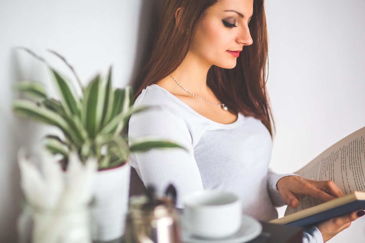 Young woman relaxing at home, reading a book about navigating her SafeMom subscription.