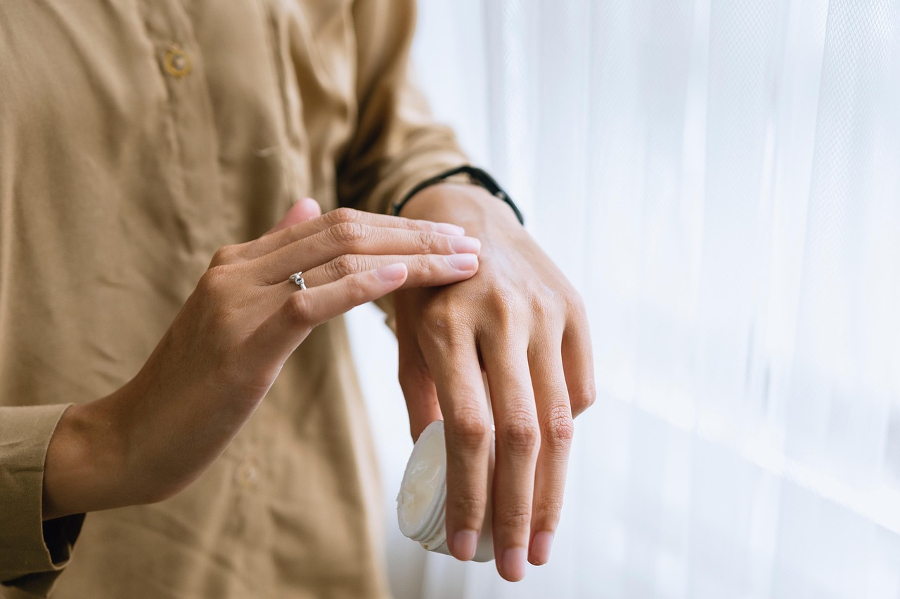 Hands apply white cream to skin, following a pregnancy skincare guide for ingredients like salicylic acid.