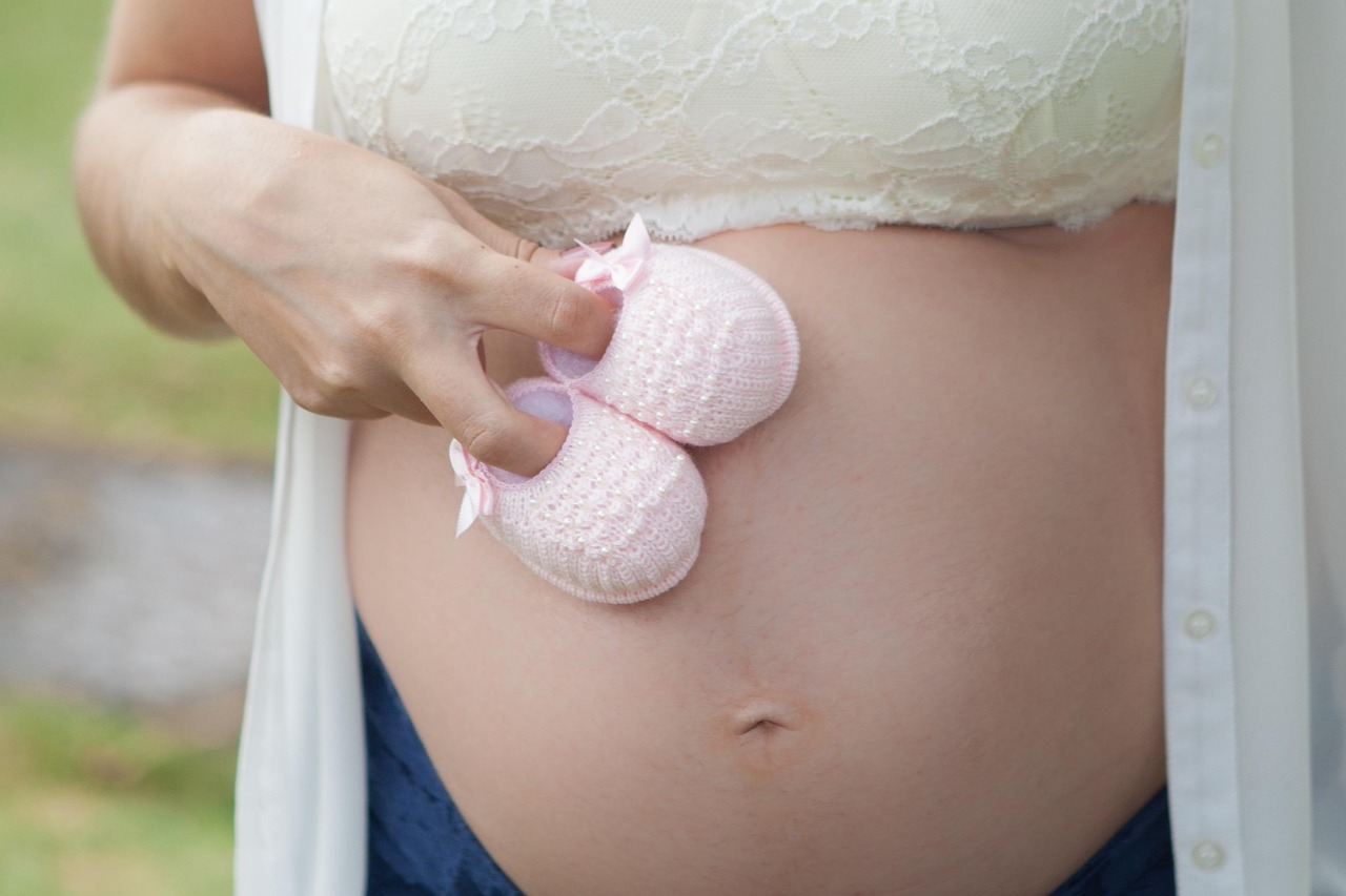 A pregnant woman with a prominent belly, ready to protect her skin from summer sun and heat.