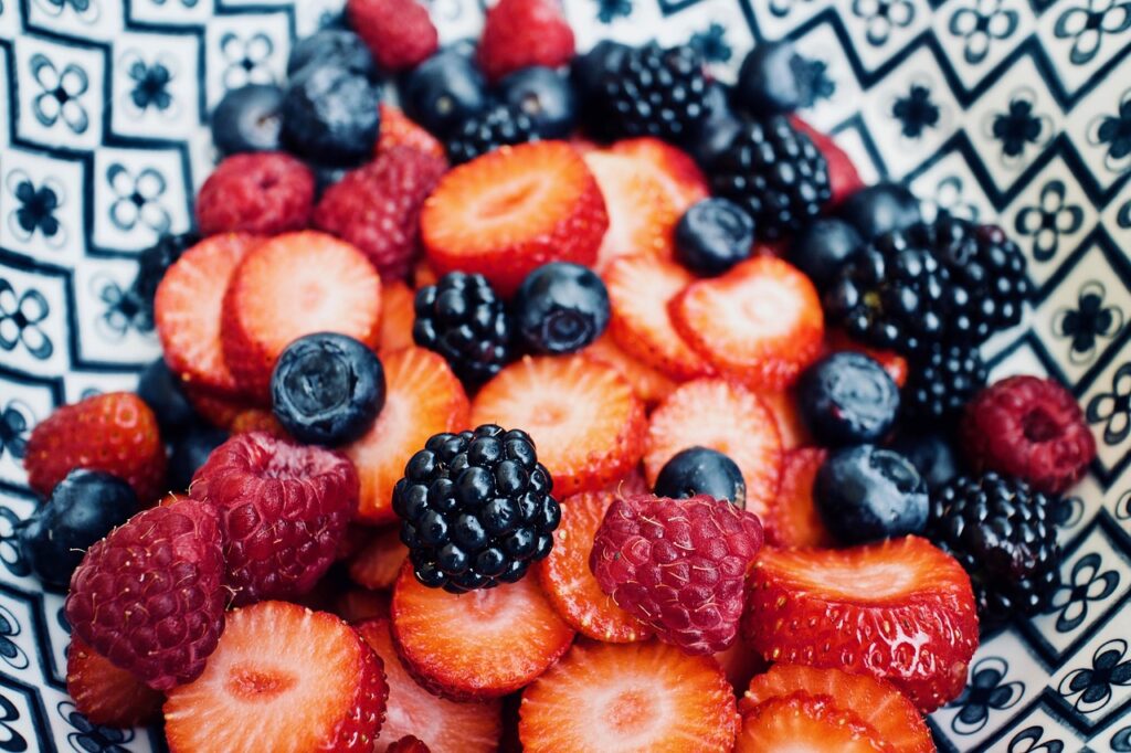 Bowl of fresh strawberries, blueberries, raspberries and blackberries on a patterned cloth