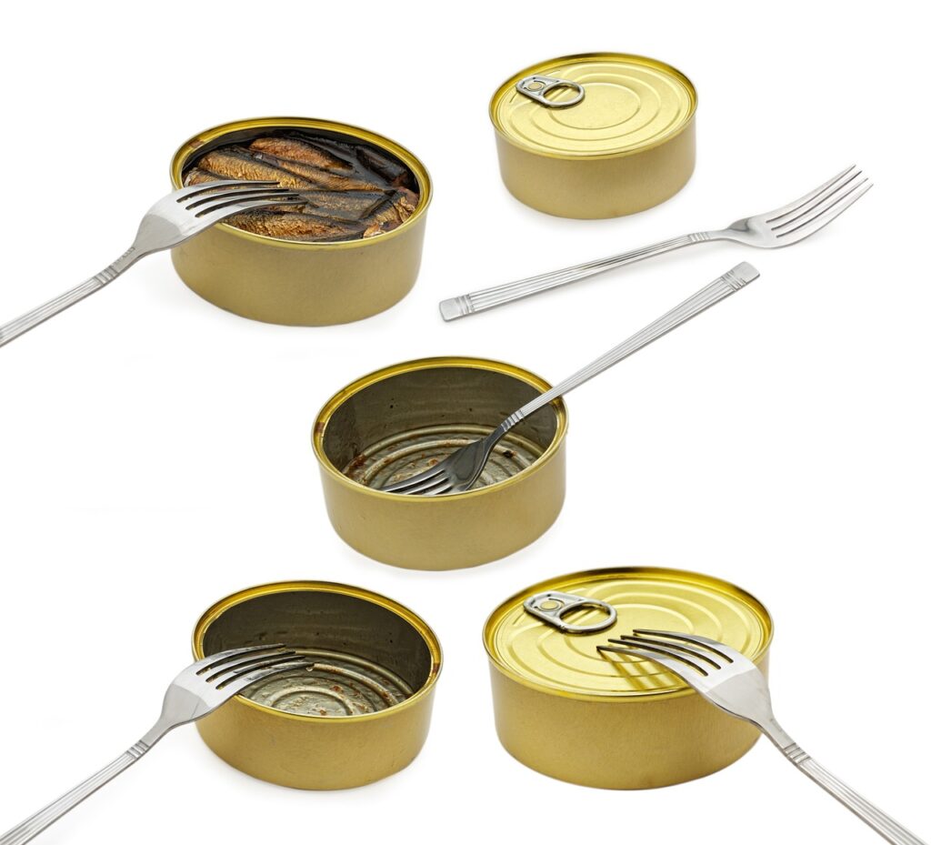 Several open tin cans of tuna with forks on a white surface, representing canned tuna