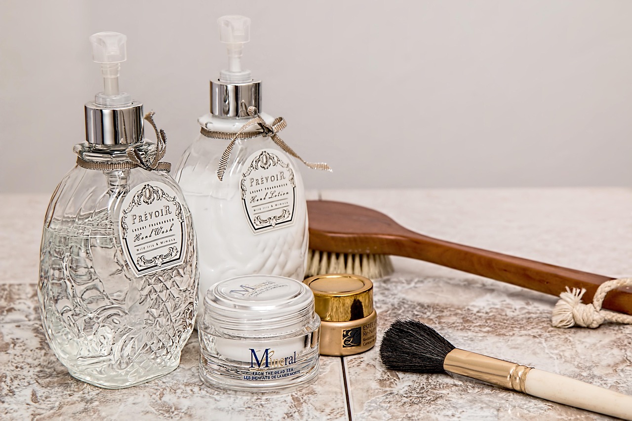 Glass pump bottles, a jar of cream and a bath brush on a marble tray, representing skincare brand choices