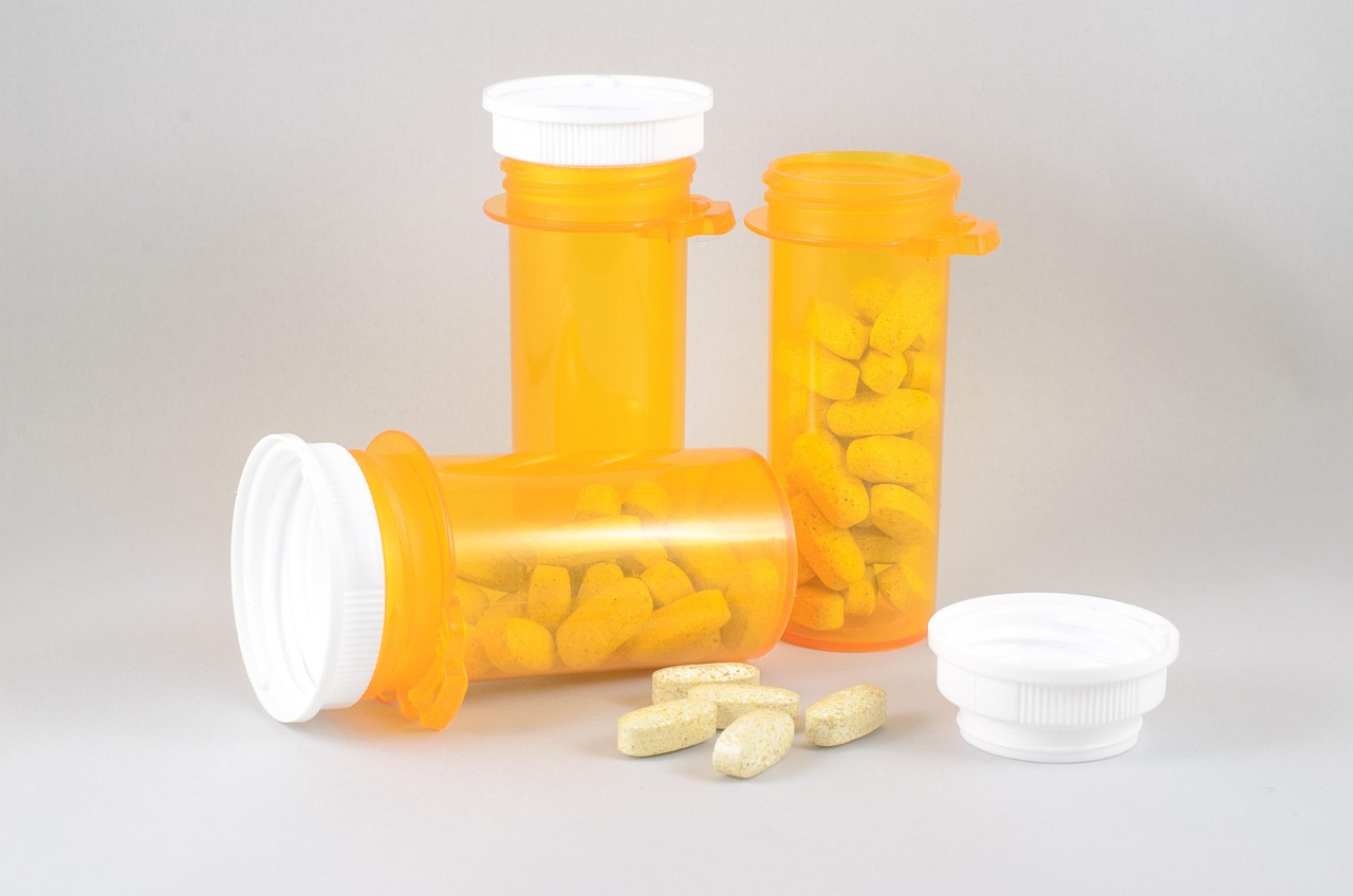 Orange plastic pill bottles with white caps and tablets on a light background, representing iron supplements