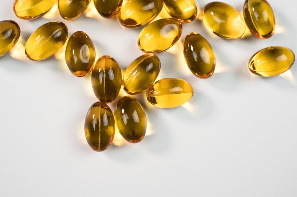 Clear golden softgel capsules scattered on a white surface, representing a stool softener like docusate