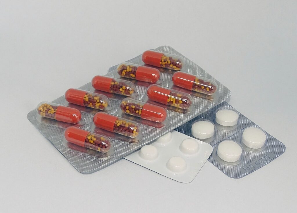 Blister packs of red-and-yellow capsules and white tablets on a grey surface, representing allergy medication