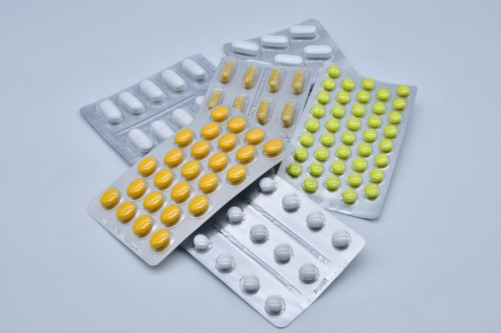 Blister packs of yellow, green and white tablets on a pale blue surface, representing diphenhydramine antihistamine medication