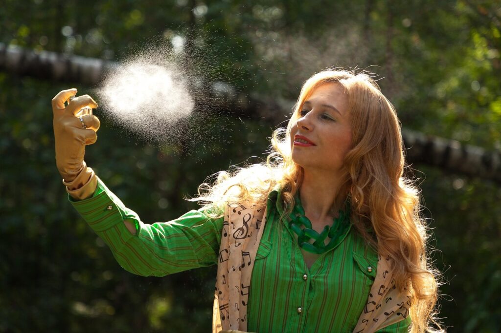 Woman spraying an aerosol mist beside her hair outdoors, representing dry shampoo aerosols