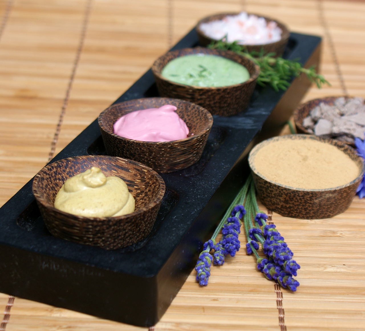 Wooden bowls of colorful natural skincare creams and lavender on a bamboo mat, everyday skincare and pregnancy safety