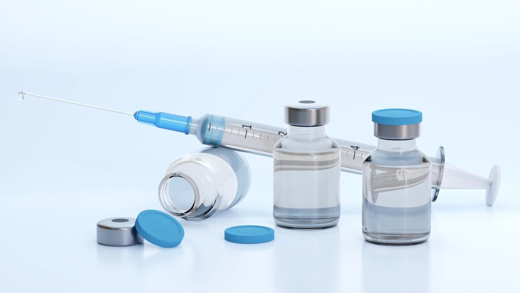 Clear glass vials and a syringe on a light surface, representing the seasonal flu vaccine in pregnancy