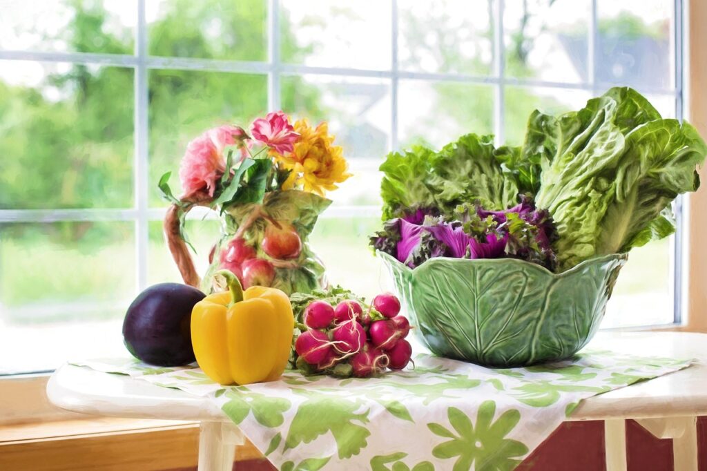 Bowl of fresh leafy greens with colorful vegetables on a sunny table, natural sources of folate