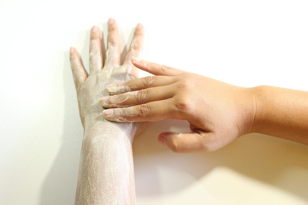 Hand with a white exfoliating scrub applied to the back of the hand, representing glycolic acid exfoliation