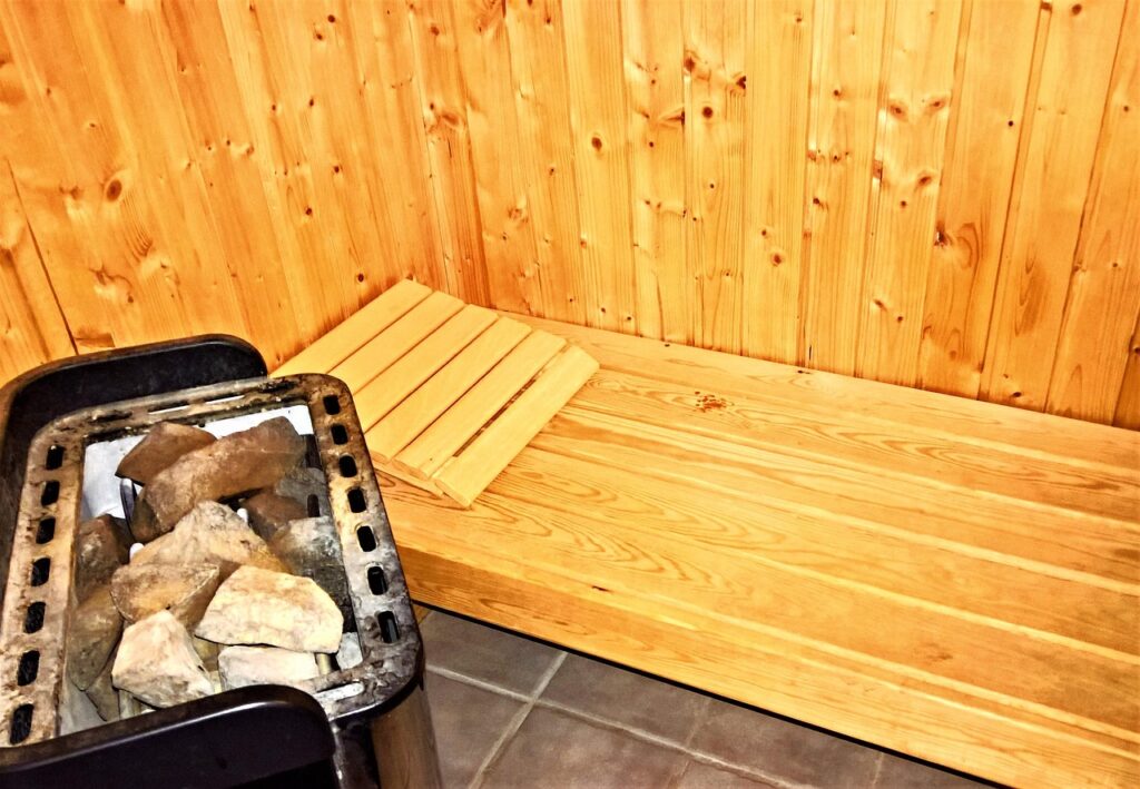Wooden sauna bench and electric stone heater inside a sauna cabin, representing hot tubs and saunas
