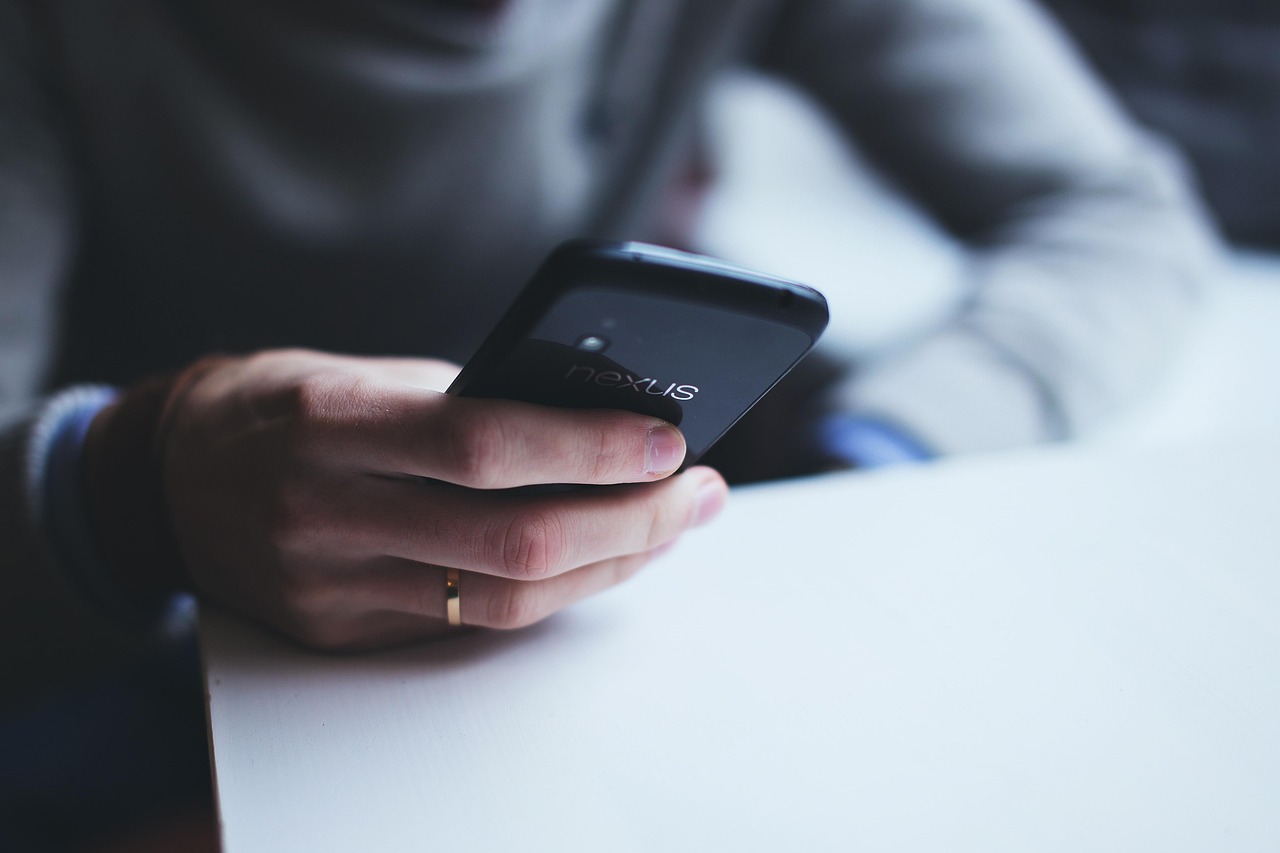 Hands holding a dark smartphone with a plain screen, checking pregnancy product safety as part of a daily routine