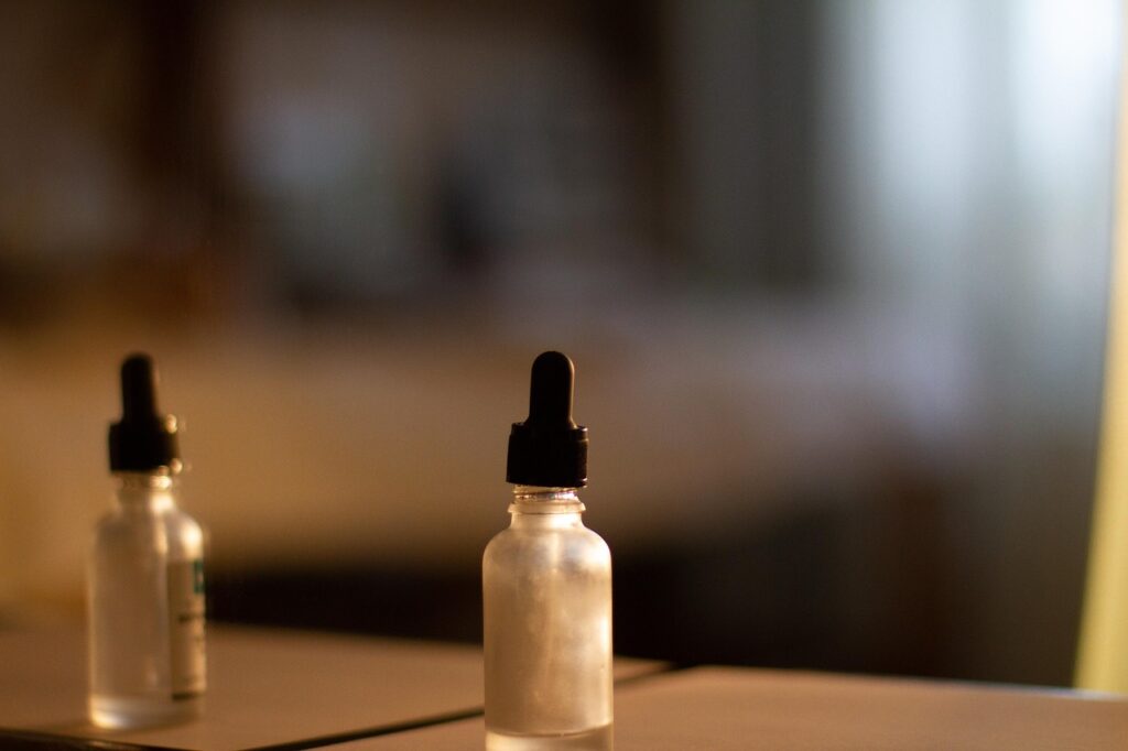 Glass dropper serum bottles on a wooden table with soft light, representing hyaluronic acid hydrating serum in pregnancy