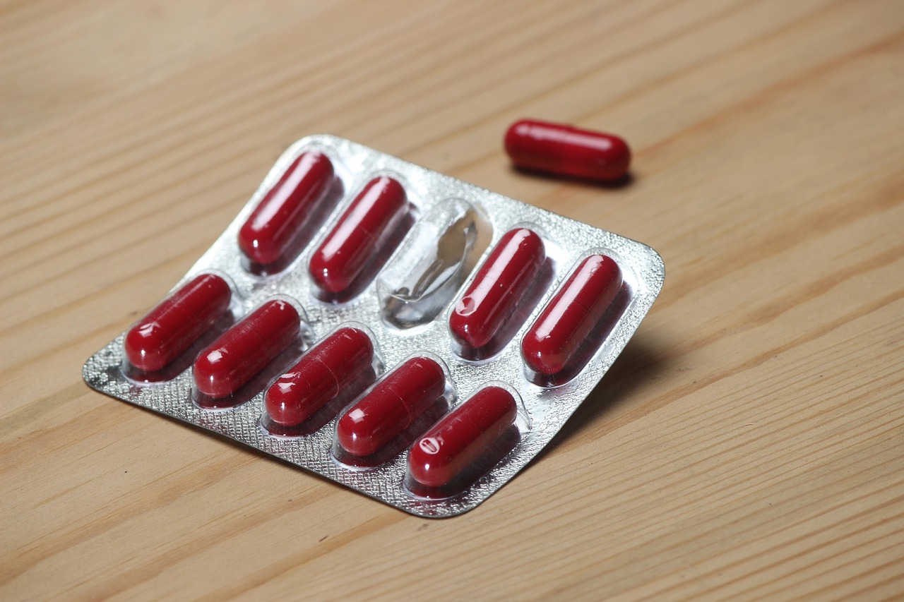 Blister pack of red capsules on a wooden table, representing oral isotretinoin capsules