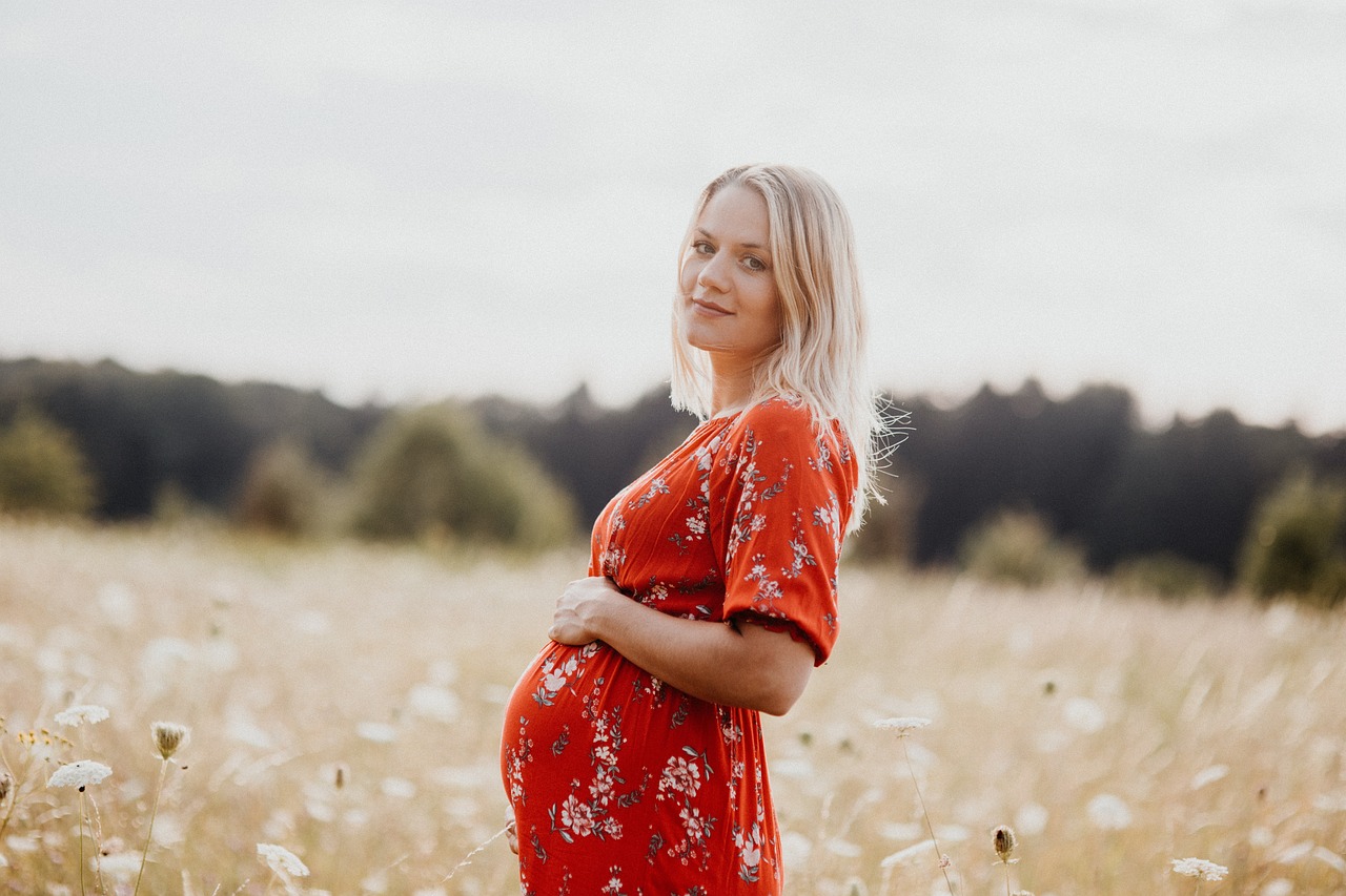 A pregnant woman smiles while cradling her belly, learning about kojic acid pregnancy.