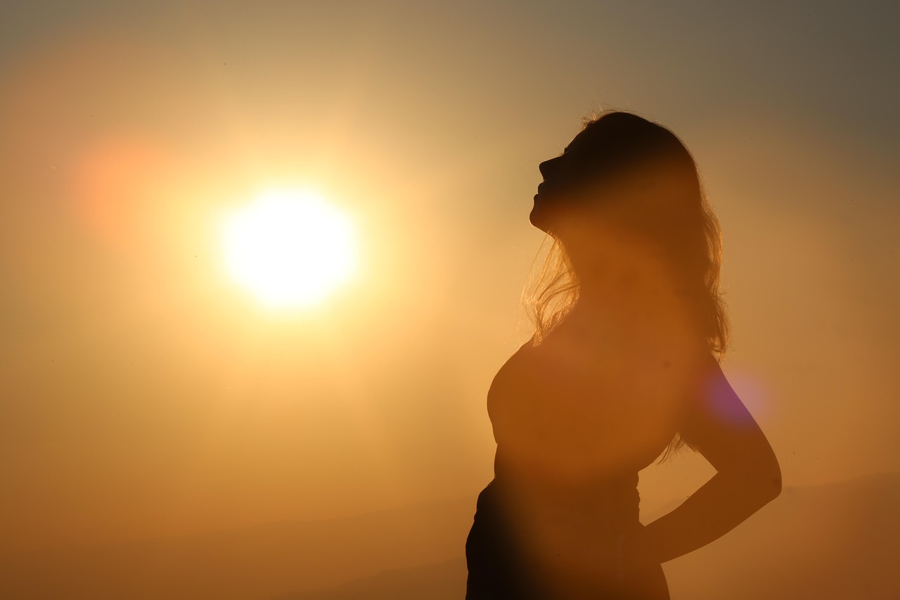 A happy pregnant woman of color's face glows in the sun, considering kojic acid pregnancy safety.
