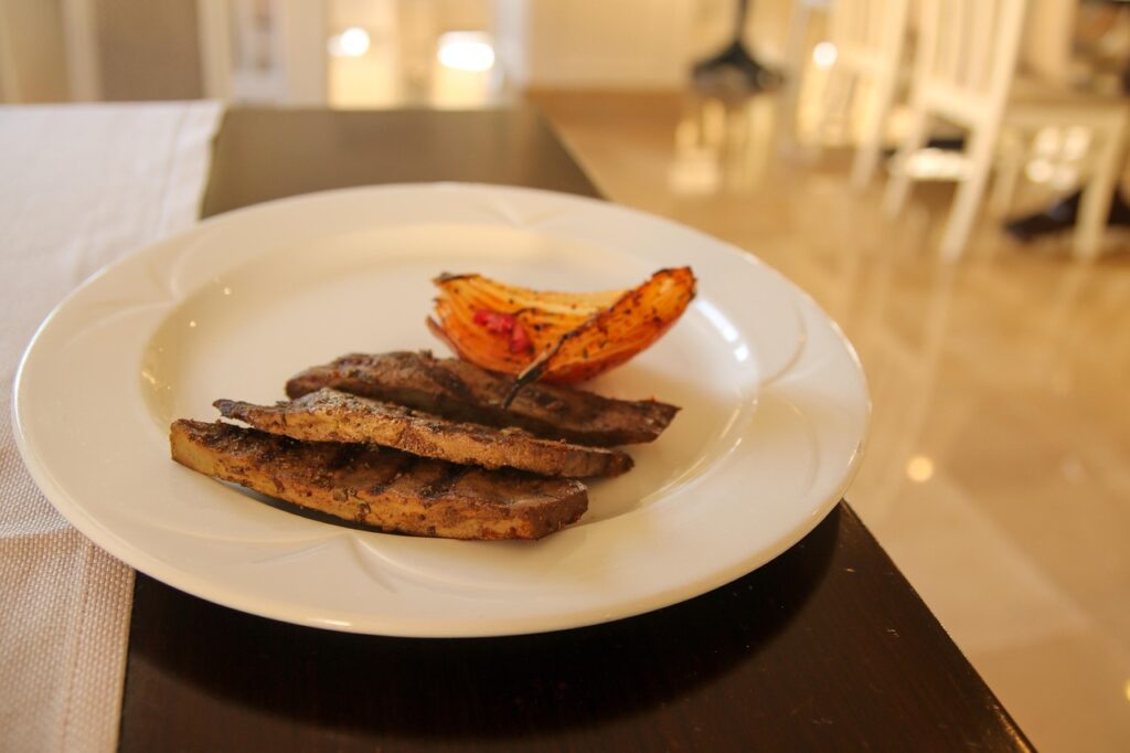 Plate of pan-seared sliced liver with roasted vegetable, representing liver as a pregnancy food