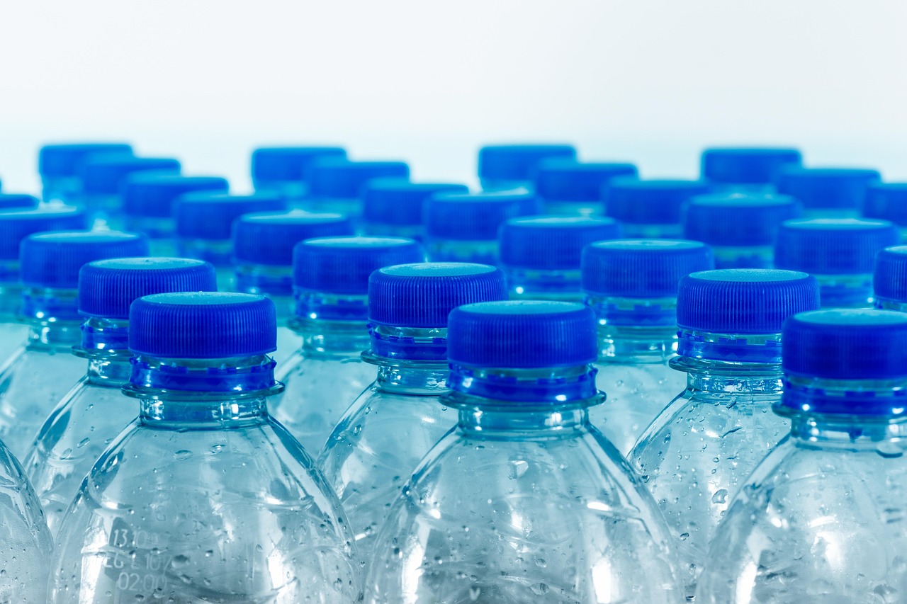 Rows of clear plastic water bottles with blue caps, representing microplastics exposure during pregnancy