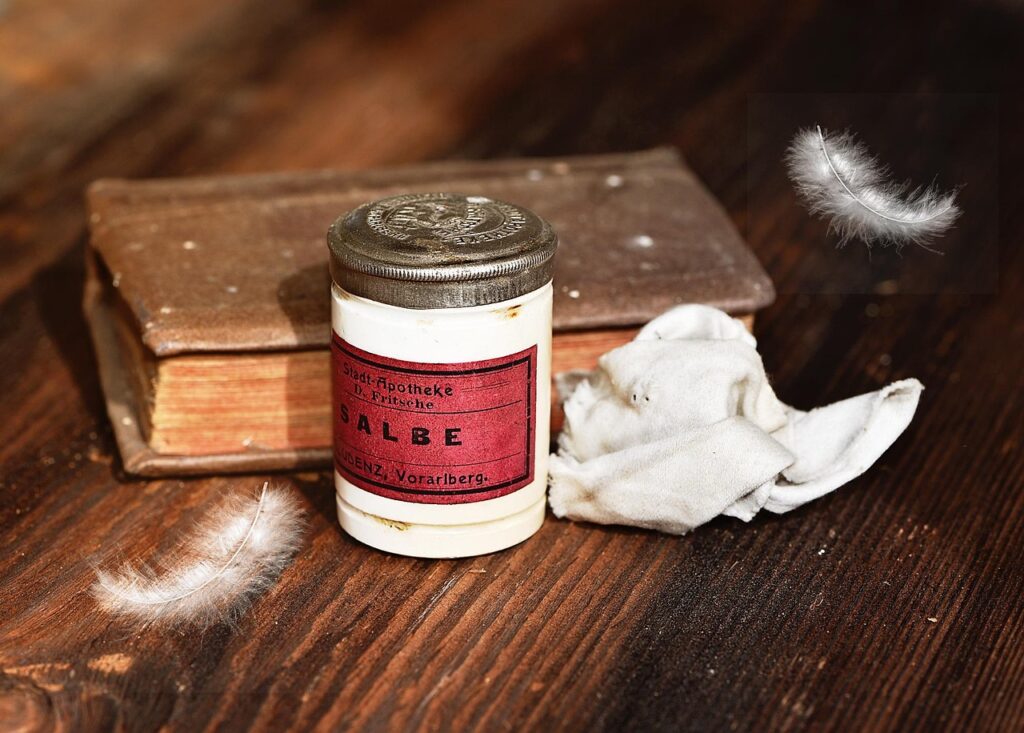 Old white ointment tin with a red label on a wooden table, representing topical antifungal creams
