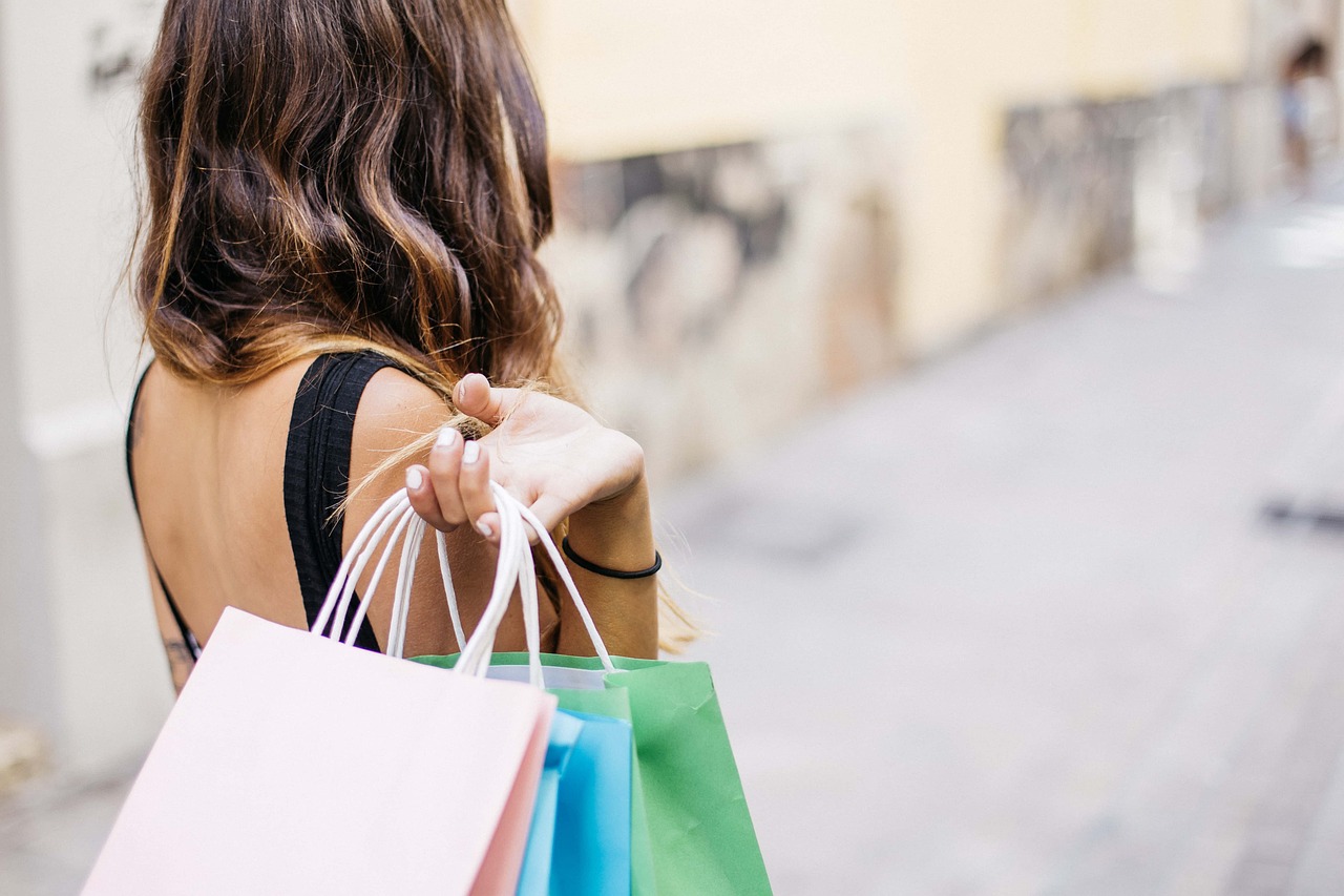Woman carrying colorful paper shopping bags along a street, representing Black Friday shopping