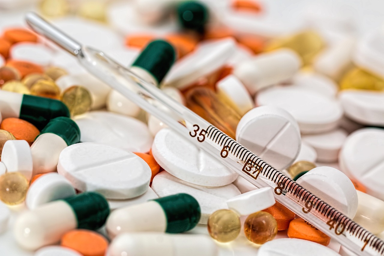 Assorted tablets and capsules with a clinical thermometer, representing cold medicine choices during pregnancy
