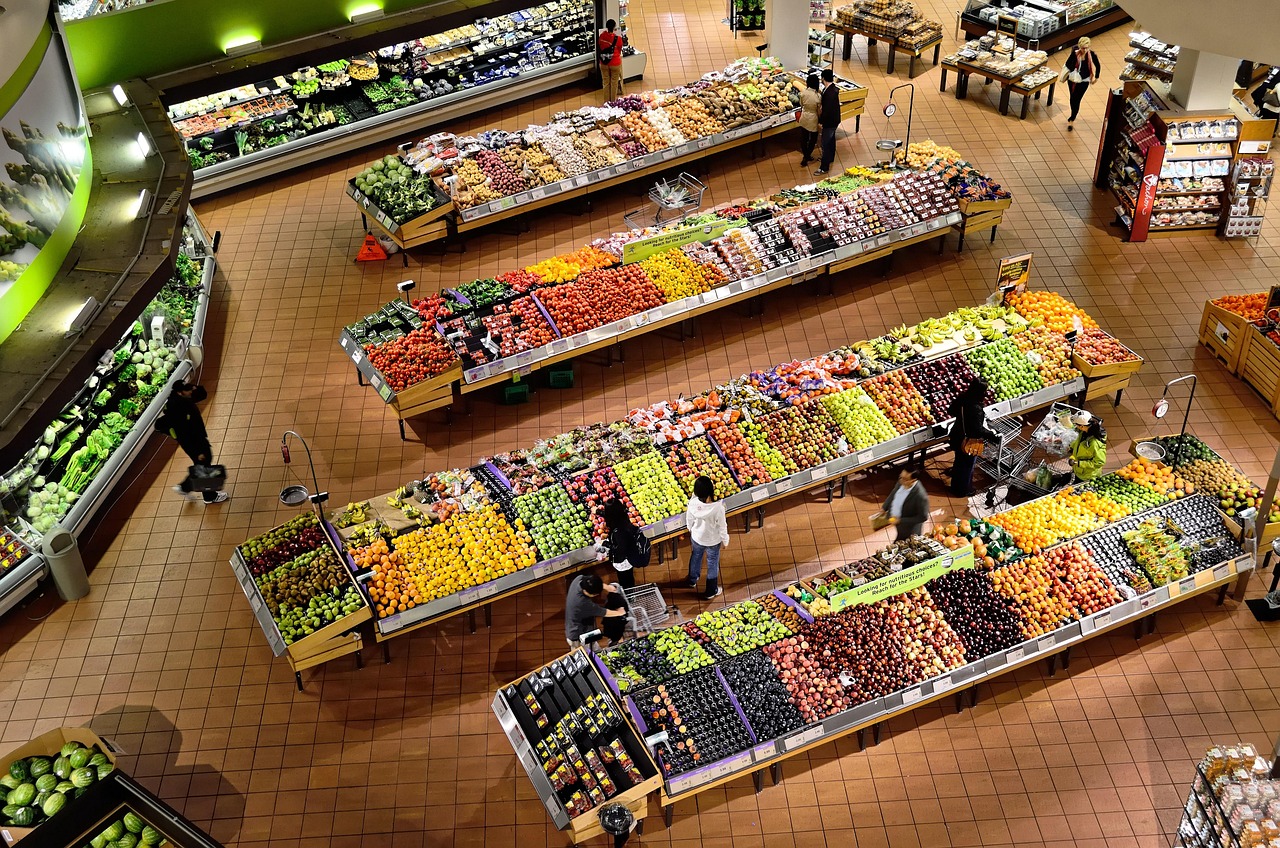 Overhead view of fresh produce stalls in a supermarket, representing food safety scanning for expecting parents
