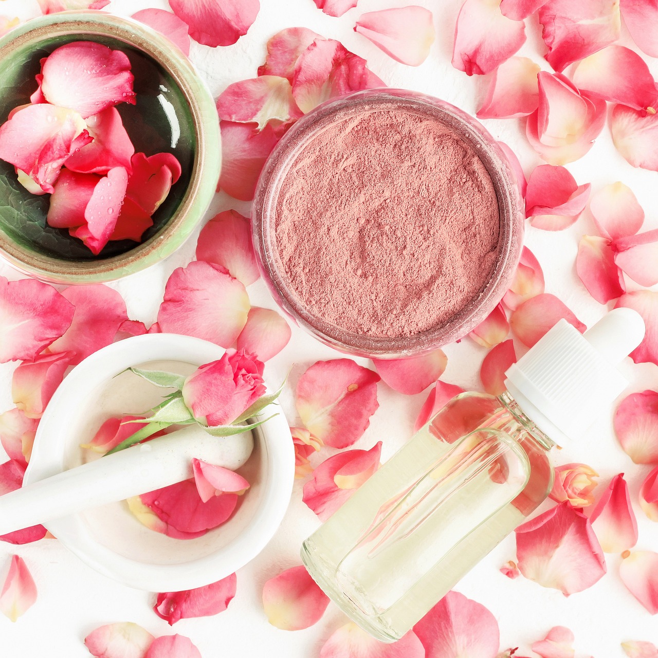 Rose petals, blush powder and a glass dropper bottle in a mortar, representing checking skincare ingredients