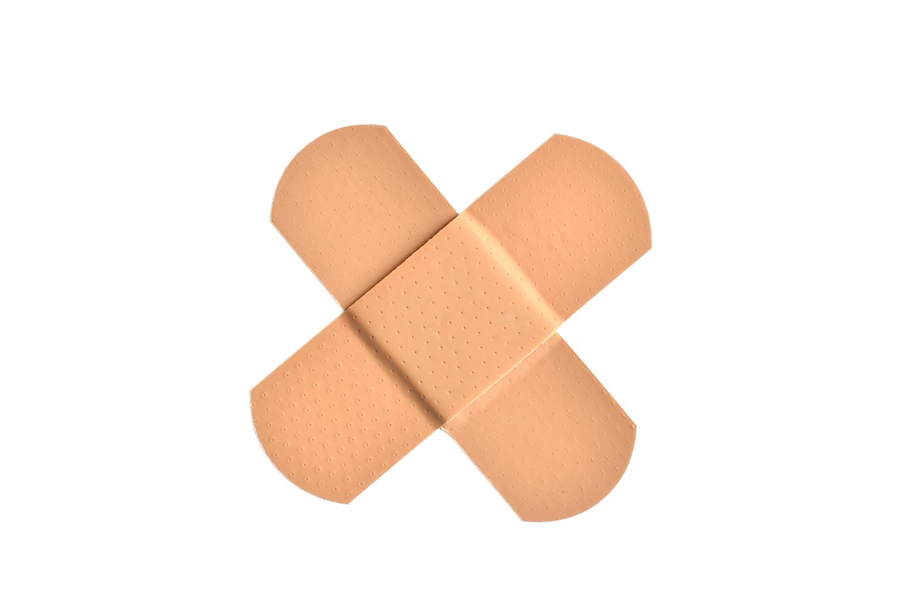 Two adhesive bandages crossed on a white background, representing first-aid care for minor cuts and antibiotic ointment use in pregnancy