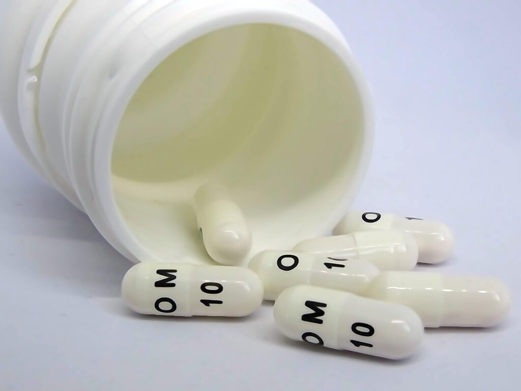 White capsules spilling from a pill bottle, representing proton pump inhibitor heartburn medication in pregnancy
