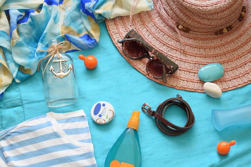 Flat lay of summer beach items including sun lotion, sunglasses and a straw hat, representing oxybenzone sunscreen