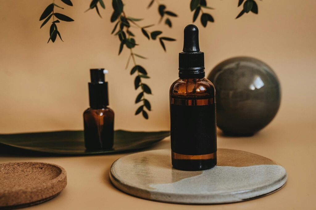 Amber glass dropper bottles of serum on a stone dish with green leaves, representing polyglutamic acid skincare