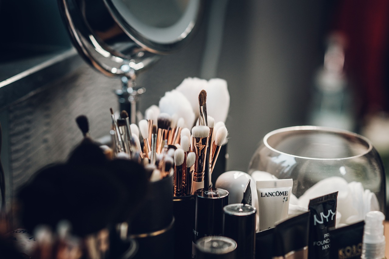Makeup brushes in holders beside a mirror on a vanity, representing cosmetics during pregnancy