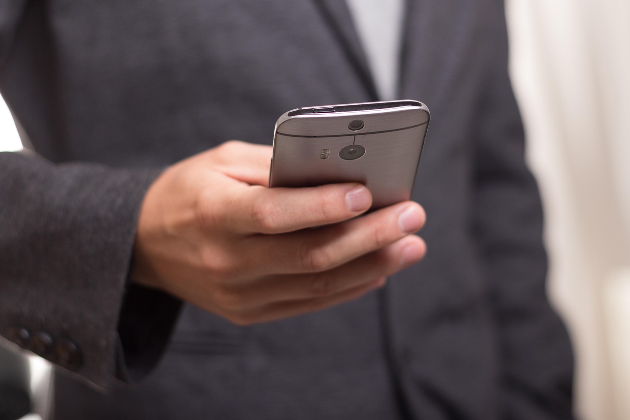 Person in a suit jacket holding a smartphone, representing using a pregnancy-safe ingredient checker app