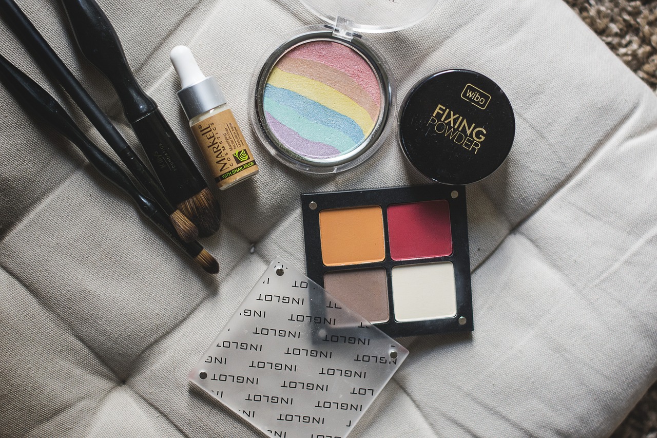Makeup palettes, brushes and compacts arranged on a cushion, representing pregnancy-safe makeup brands
