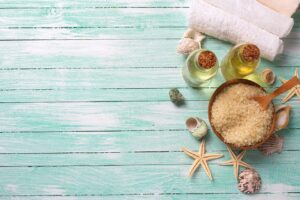 Glass oil bottles, coconut oil and white towels on a turquoise wooden table, representing natural pregnancy-safe skincare
