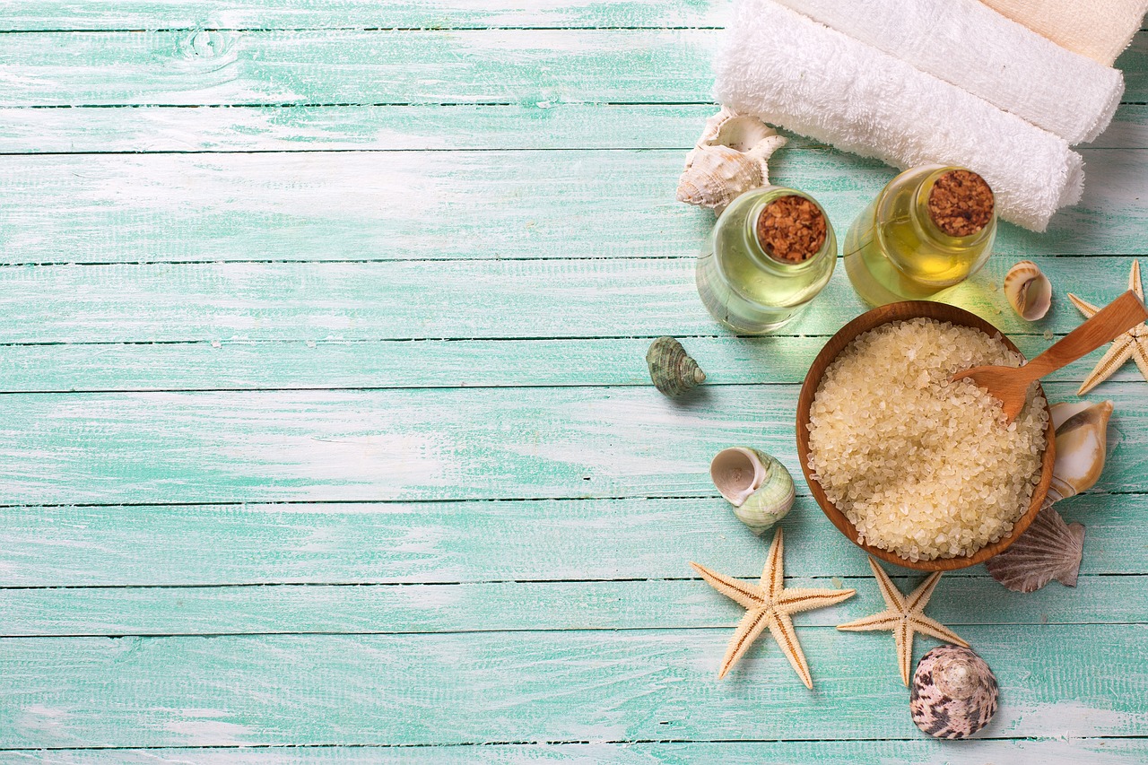 Glass oil bottles, coconut oil and white towels on a turquoise wooden table, representing natural pregnancy-safe skincare