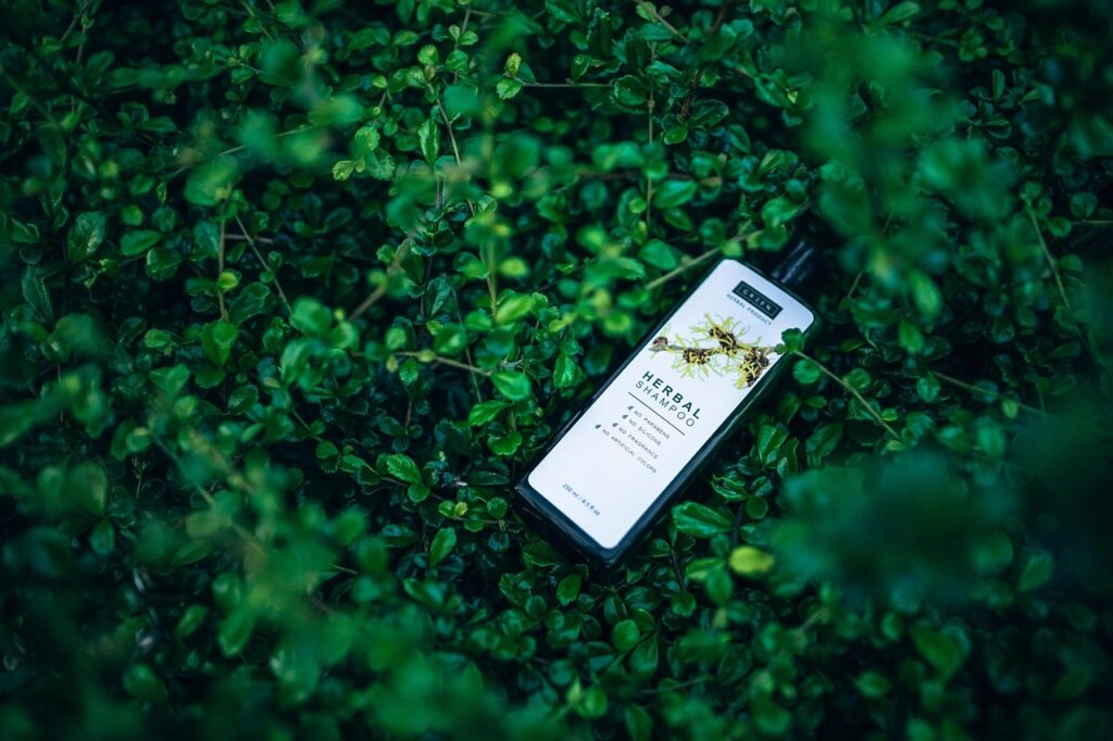 Herbal shampoo bottle lying on green leafy foliage, representing pregnancy-safe shampoo and conditioner choices