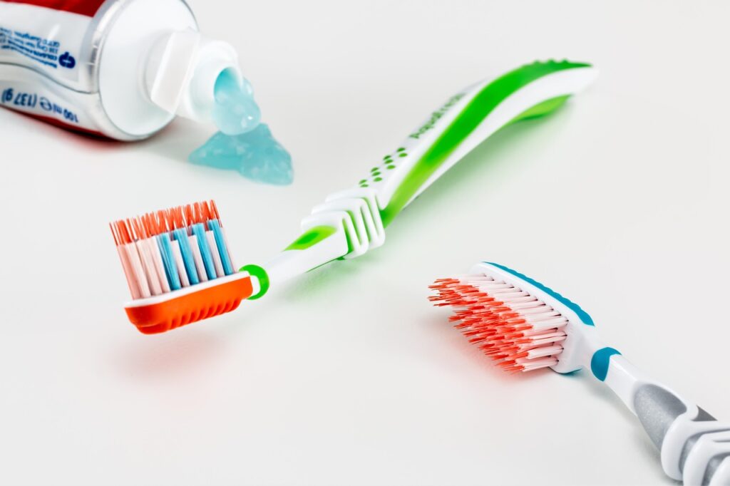 Colorful toothbrushes beside a squeeze of toothpaste and a tube on a white surface, representing pregnancy-safe toothpaste