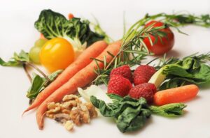 Fresh carrots, raspberries, spinach, walnuts and vegetables arranged together, representing first trimester prenatal nutrition