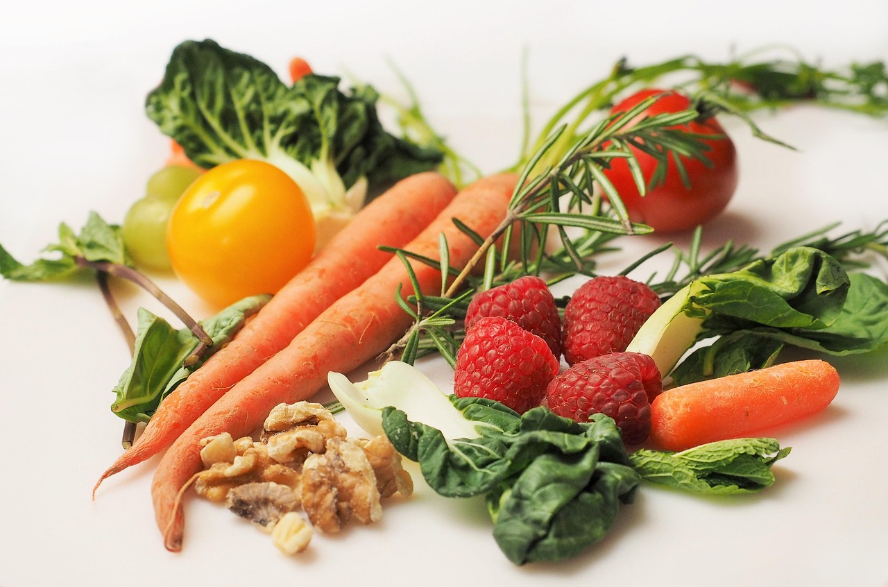 Fresh carrots, raspberries, spinach, walnuts and vegetables arranged together, representing first trimester prenatal nutrition