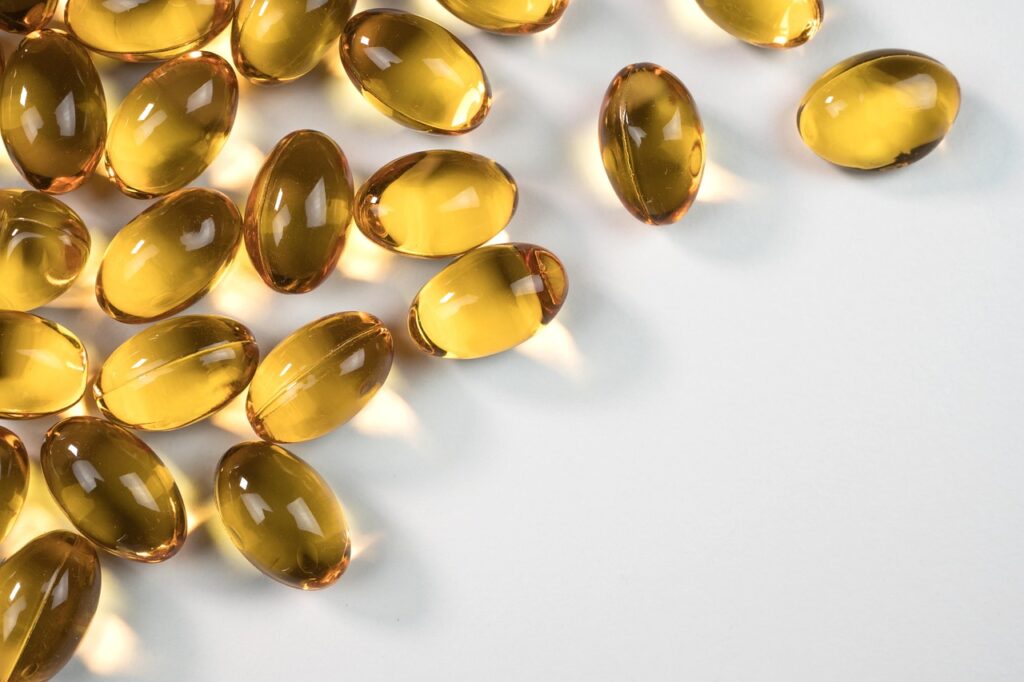 Golden translucent softgel supplement capsules on a white surface, representing prenatal vitamins